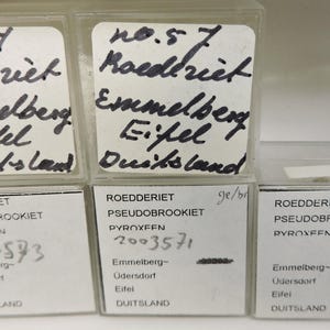 Könnte beinhalten: Eine Sammlung kleiner, durchsichtiger Plastikboxen mit handschriftlichen Etiketten. Die Etiketten tragen die Aufschrift "Roederiet", "Emmelberg" und "Eifel, Deutschland". Die Boxen sind in einem Raster angeordnet.