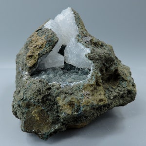 Puede incluir: Una roca con una cavidad llena de cristales blancos y cristales verdes más pequeños.