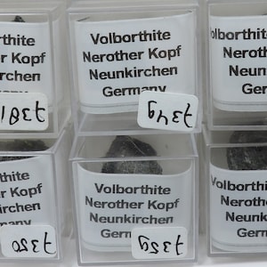 May include: Six small clear plastic boxes with black labels containing small gray rocks. The labels read "Volborthite, Nerother Kopf, Neunkirchen, Germany" and include a price in Euros.