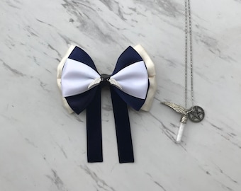May include: A navy blue and white bow tie with two long tails. A silver necklace with a vial and a star pendant.