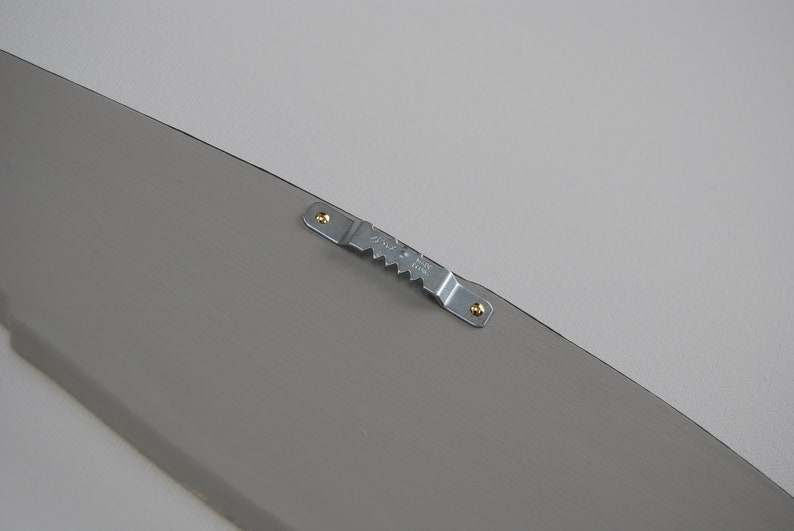 May include: A gray, wooden decorative piece with a metal sawtooth hanger attached. The hanger is secured with two small screws. The item is painted a solid gray color.