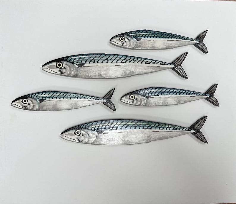 May include: Five mackerel fish illustrations with detailed scales and fins. The fish are primarily silver with blue-green markings along their backs. The artwork is set against a plain white background, creating a clean and simple aesthetic.