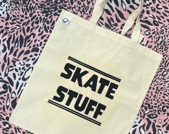 Könnte beinhalten: Eine beige Canvas-Tragetasche mit schwarzen Henkeln und dem aufgedruckten Text "SKATE STUFF" in Schwarz.