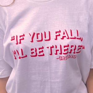 May include: White t-shirt with red text that reads "#IF YOU FALL, I'LL BE THERE" -GRYFINO