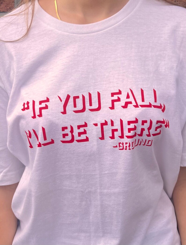 May include: White t-shirt with red text that reads "#IF YOU FALL, I'LL BE THERE" -GRYFINO