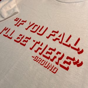 May include: White t-shirt with red text that reads "If you fall I'll be there - GROUND".