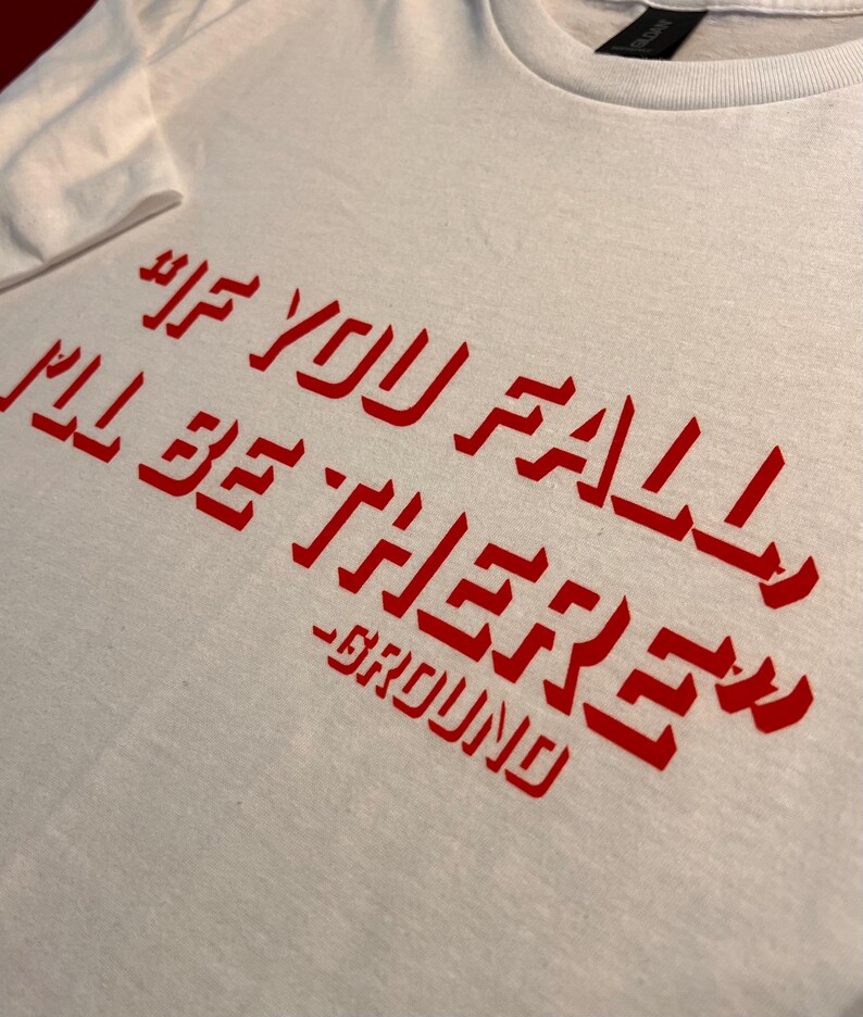 May include: White t-shirt with red text that reads "If you fall I'll be there - GROUND".