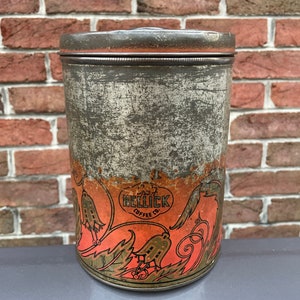 May include: Vintage metal coffee tin with a distressed finish. The tin features a design with orange and gold floral elements and the text "Hellick Coffee Co." The cylindrical container has a lid.