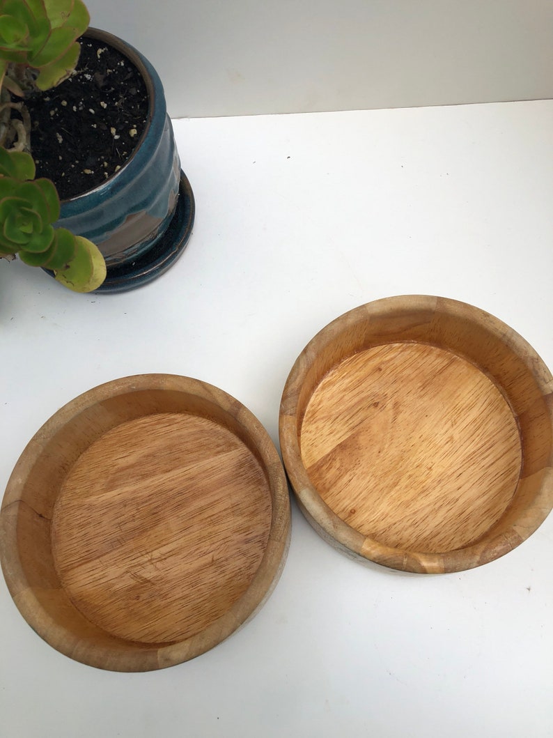 Peut inclure: Deux bols en bois, l'un l&eacute;g&egrave;rement plus grand que l'autre, sont pr&eacute;sent&eacute;s sur une surface blanche. Les bols sont en bois brun clair et ont une finition lisse et polie.
