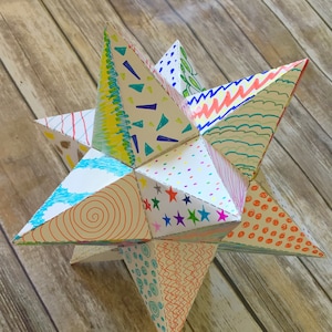 Könnte beinhalten: Ein farbenfroher, papierner Stern-Dodekaeder mit verschiedenen Mustern und Designs. Der Dodekaeder besteht aus 12 fünfeckigen Flächen und ist eine dreidimensionale geometrische Form.