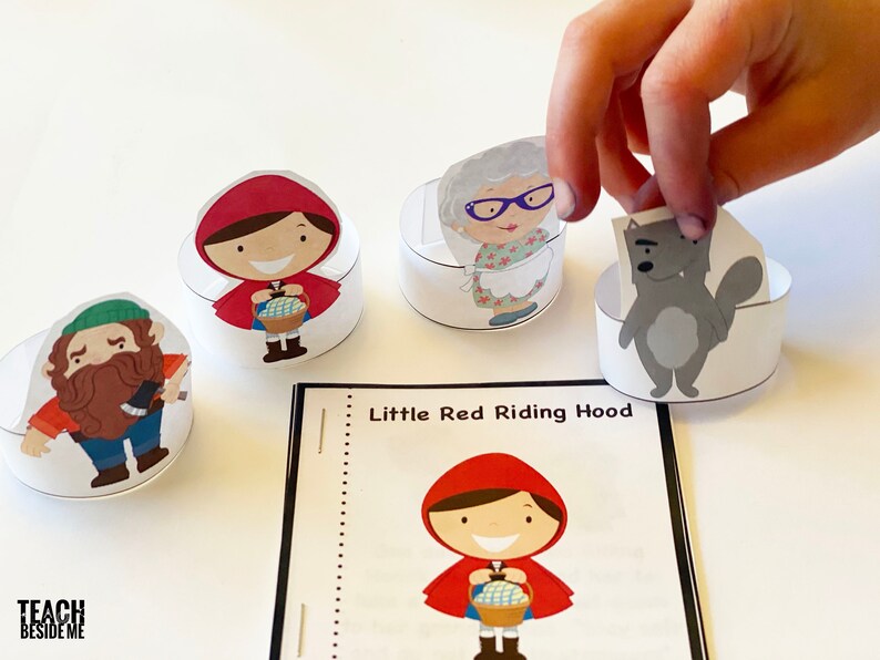 May include: A set of five paper character cutouts for a Little Red Riding Hood story. The characters include Little Red Riding Hood, the wolf, the grandmother, and the woodcutter. The characters are on a white background.