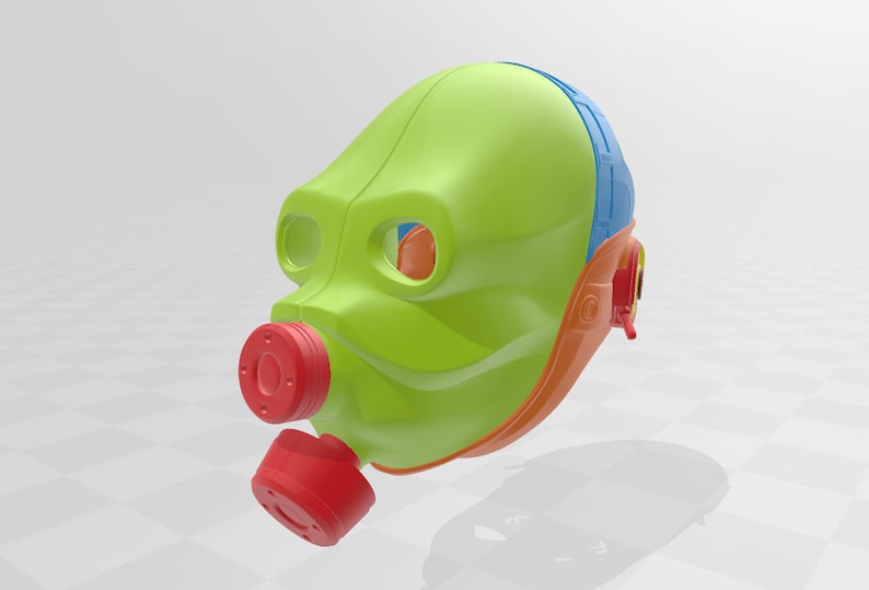 May include: A green, orange, and blue plastic mask with a red mouthpiece. The mask has a rounded shape and a design that resembles a face.