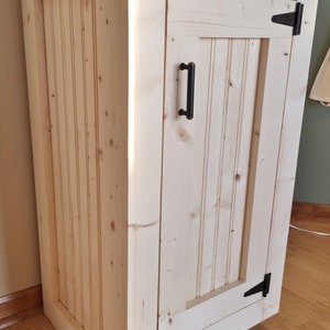 Raw pine vanity base seen from the side, showing the beadboard side panel