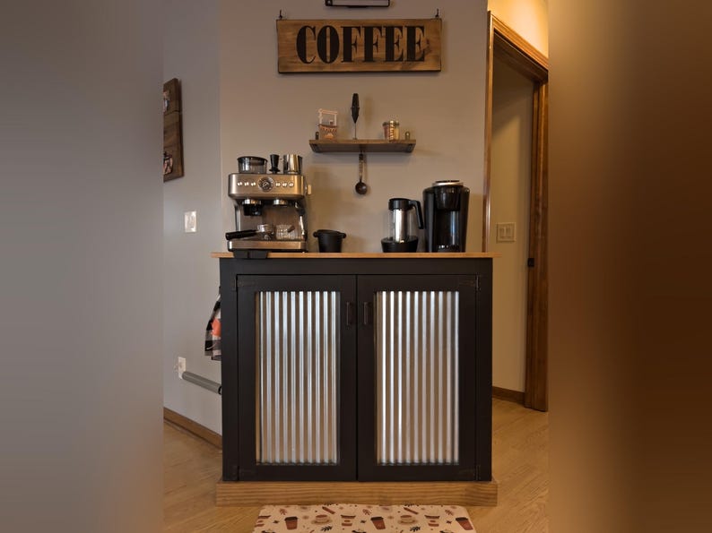 Farmhouse Coffee Bar Cabinet painted black with corrugated metal doors, in a home coffee station under a wood COFFEE sign and a small wall shelf