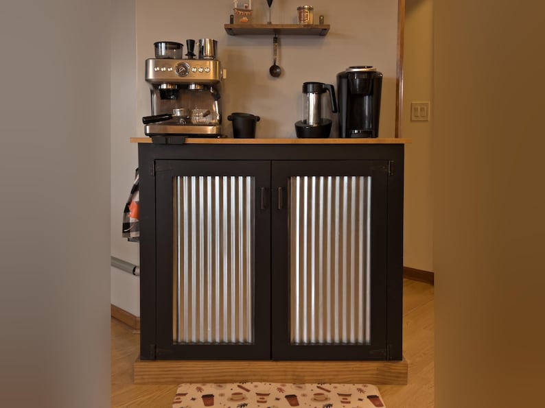 Farmhouse Coffee Bar Cabinet painted black, with corrugated metal doors and a stained top and base trim, set up as a coffee bar with an espresso machine and a coffee maker