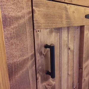 Close-up of the oil-rubbed bronze handle and T-hinge on the stained beadboard door