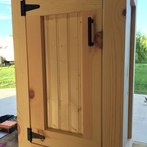 Raw unfinished pine vanity base with a beadboard door, ready for your own stain or paint