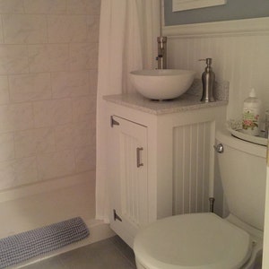 White painted pine vanity base with a vessel sink in a half bath beside the toilet