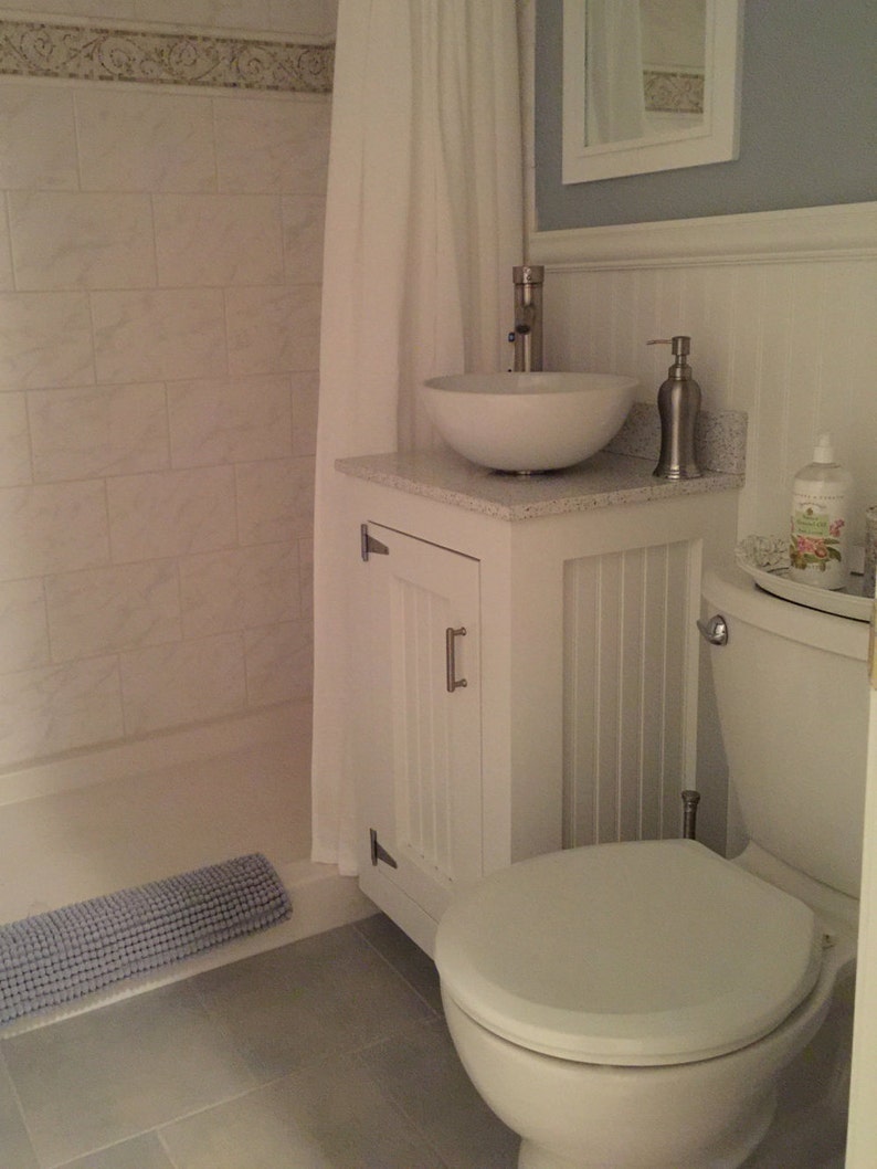 White painted pine vanity base with a vessel sink in a half bath beside the toilet