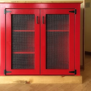 Farmhouse Coffee Bar Cabinet painted red, with welded wire mesh doors, black T-hinges, bar pulls and a stained planked pine top and base trim