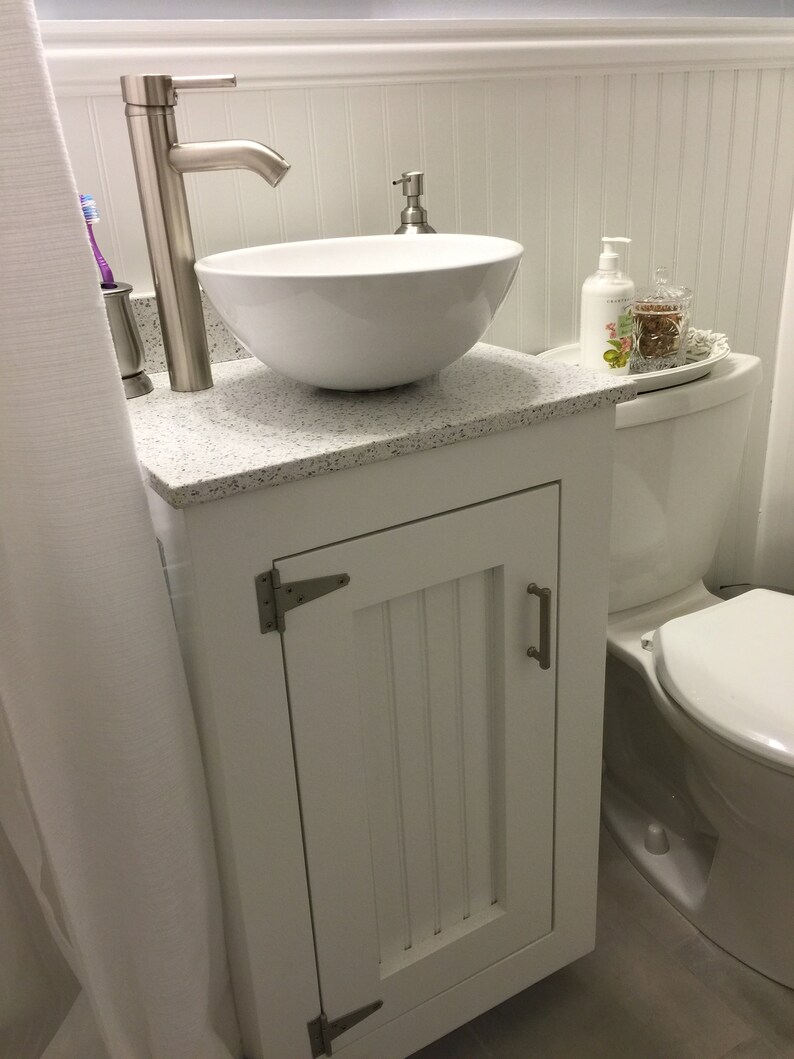 The same vanity base painted white, with satin nickel hinges and handle (on request), a granite top and a white vessel sink in a small bathroom