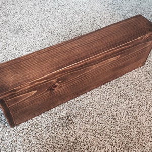 One stained knotty pine floating shelf, showing its square front, top and end