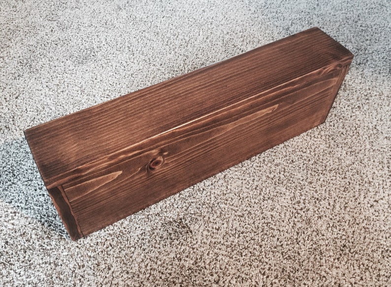 One stained knotty pine floating shelf, showing its square front, top and end