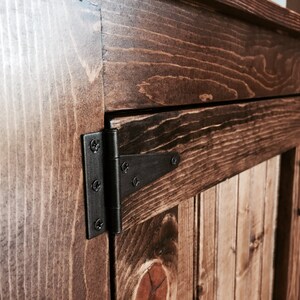 Close-up of the oil-rubbed bronze hinge on the vanity's beadboard door