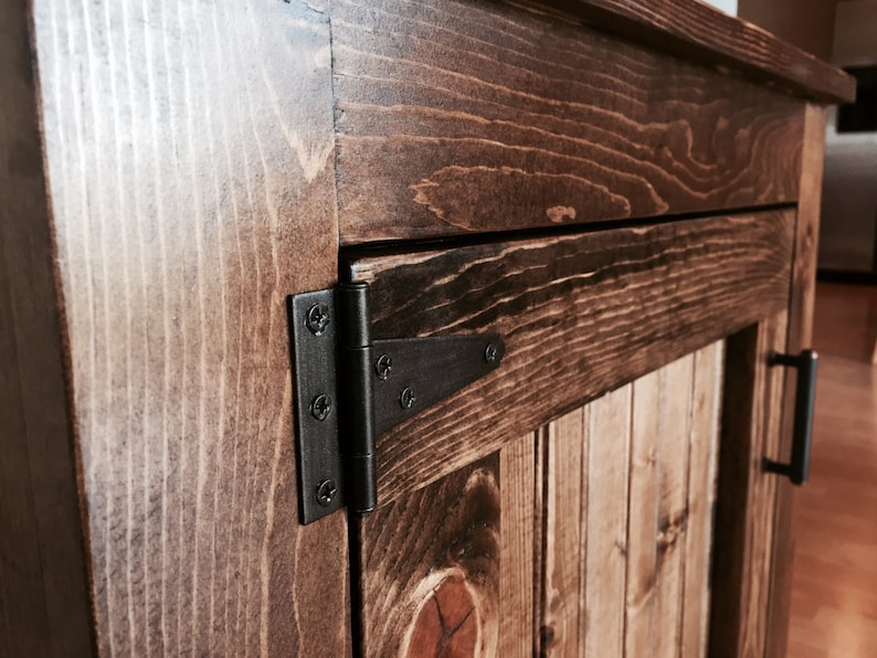 Close-up of the oil-rubbed bronze hinge on the vanity's beadboard door