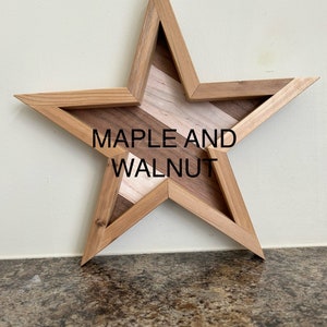 May include: A wooden star-shaped wall decoration with a maple and walnut inlay. The star is made of light brown wood and has a natural wood finish.
