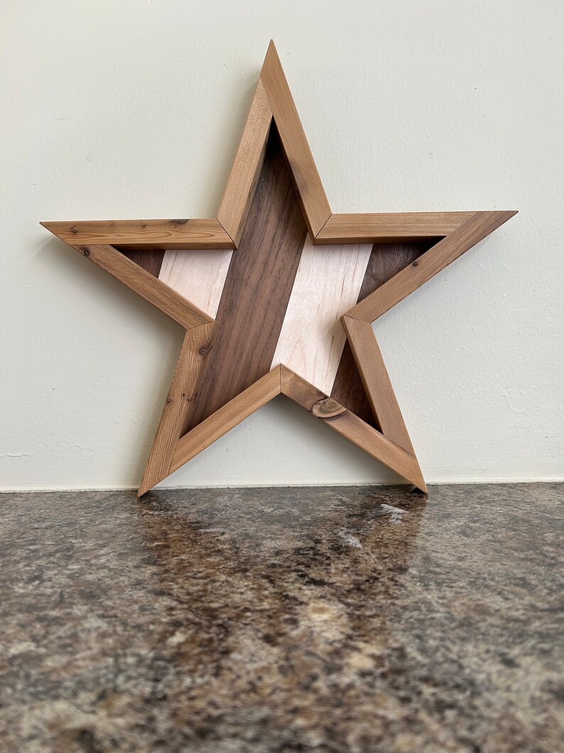 May include: A wooden star-shaped wall decoration with a geometric design. The star is made of different types of wood, including walnut and maple, and has a natural wood finish.