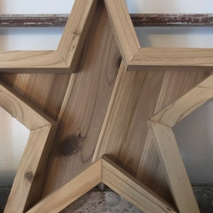 May include: A large wooden star with a rustic finish. The star is made of multiple pieces of wood that are joined together to create a three-dimensional shape.