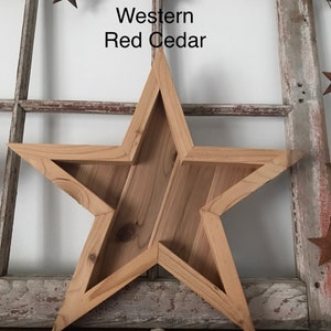May include: A large wooden star-shaped wall decoration made of Western Red Cedar. The star is unfinished and has a rustic look.