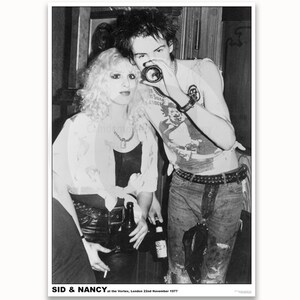 May include: Black and white photo of a couple, Sid and Nancy, at the Vortex in London on November 22, 1977.  Sid is wearing a t-shirt, jeans, and a belt with studs. Nancy is wearing a white shirt, black leather pants, and a necklace.