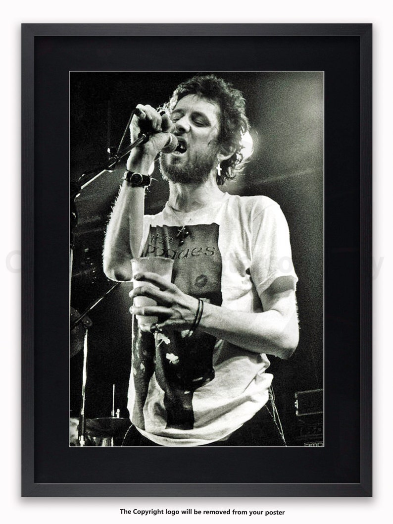 K&ouml;nnte beinhalten: Schwarz-wei&szlig; gerahmtes Poster einer Live-Musikauff&uuml;hrung. Eine Person singt in ein Mikrofon und h&auml;lt einen Becher. Die Person tr&auml;gt ein T-Shirt mit dem Aufdruck "Pogues". Das Bild befindet sich in einem schwarzen Rahmen.