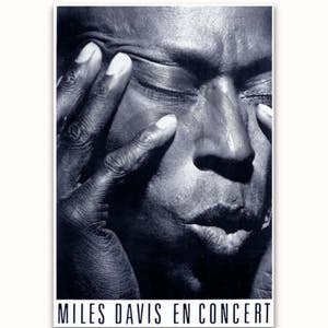 May include: Black and white photo of Miles Davis, a famous jazz musician, with his eyes closed and his hand covering part of his face. The text "MILES DAVIS EN CONCERT" is at the bottom of the photo.