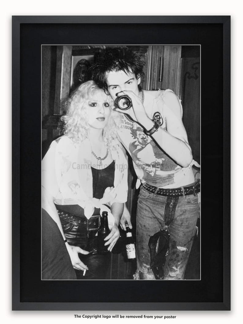 May include: Black and white photograph of a couple, a woman with blonde hair and a man with dark hair, standing close together. The woman is wearing a white shirt and a black leather jacket. The man is wearing a white t-shirt with a graphic design and a black leather jacket. They are both holding bottles of beer.