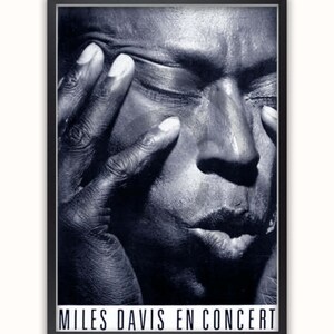 May include: Black and white close-up portrait of Miles Davis, a famous jazz musician, with the text "Miles Davis En Concert" at the bottom of the image.