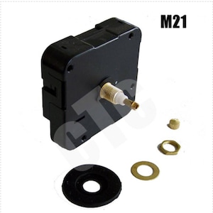 May include: A black clock movement with a gold winding stem and a gold nut. The movement is labeled "M21".