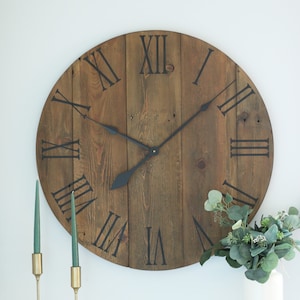 May include: A large, round, wooden clock with Roman numeral markings and black hands. The clock face is made of reclaimed wood planks.