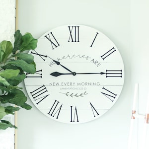 May include: White wooden clock with black Roman numeral markings and black hands. The clock face has the text "His mercies are new every morning" and "Lamentations 3:22-23".