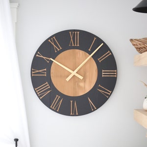 May include: A large, round clock with black and wood accents. The clock face has Roman numerals and gold-colored hands.