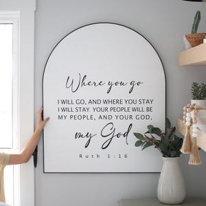 Puede incluir: Un letrero blanco en forma de arco con borde negro y el texto "Where you go I will go, and where you stay I will stay. Your people will be my people, and your God, my God. Ruth 1:16"