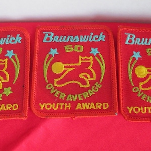 May include: Three red embroidered patches with the text "Brunswick" and "Youth Award". The left patch has the text "150" and the right two patches have the text "50" and "Over Average".