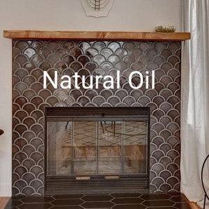 May include: A fireplace with a dark gray tiled surround and a black metal fireplace screen. The tile is arranged in a fish scale pattern. The text "Natural Oil" is written in white on the tile.
