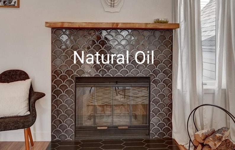 May include: A fireplace with a dark gray tiled surround and a black metal fireplace screen. The tile is arranged in a fish scale pattern. The text "Natural Oil" is written in white on the tile.
