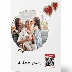 May include: A white greeting card with a photo of a woman and two children. The photo is surrounded by a brown circle with decorative elements. The card has the text "I Love you" and a QR code that says "SCAN ME". Two red heart shapes are in the upper right corner.