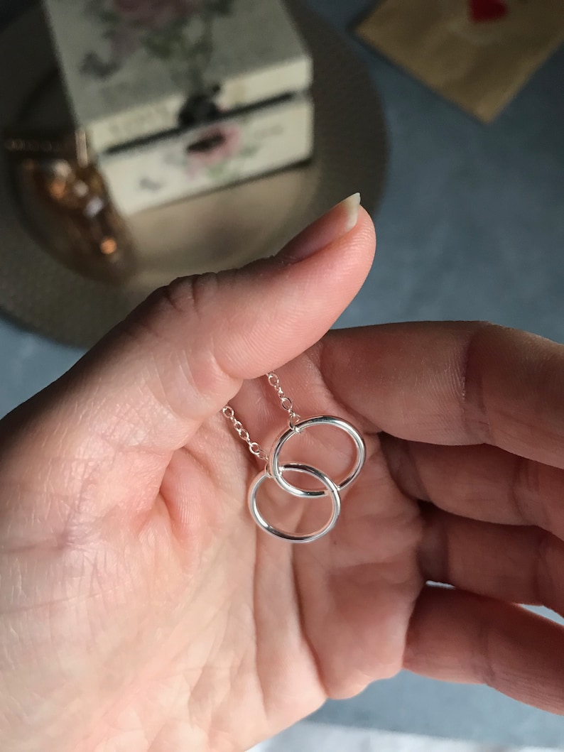 May include: A silver necklace with two interlocking circles as a pendant.