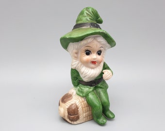 Seated Baby Green Elf Pixie Leprechaun Figurine Holding Shamrocks Clovers Peapod Green Suit Flower Hat Brown Hair Japan 1970s