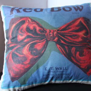 K&ouml;nnte beinhalten: Ein Dekokissen mit einem roten Schleifendesign und dem Text "Red Bow Brand" und "E.T. Wall Grower-Shipper Riverside, Kalifornien Produce of U.S.A."